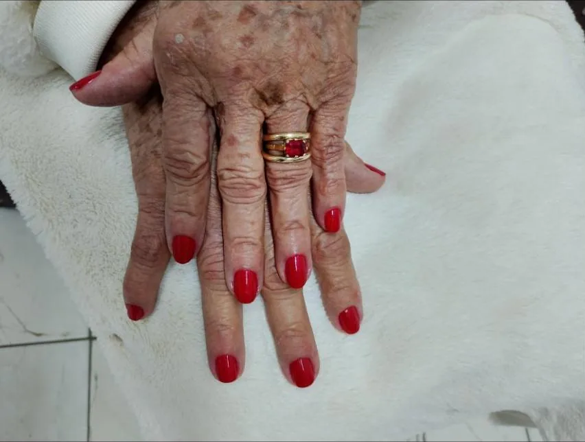 Mão com unhas vermelhas e anel com pedra vermelha